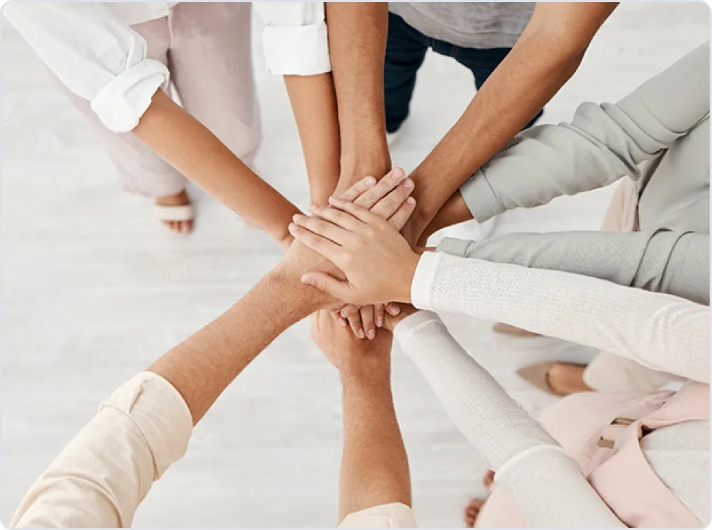Hands of a diverse team stacked together in the centre, symbolising unity